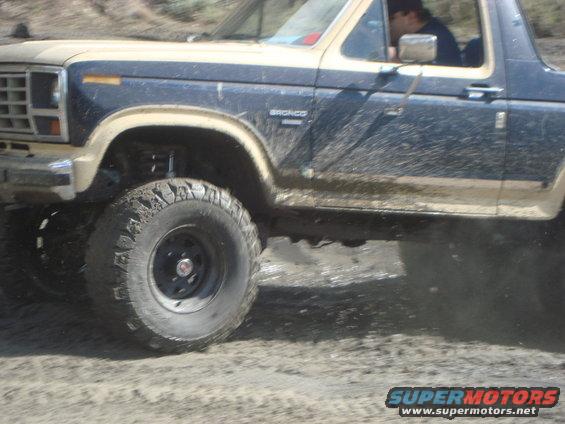 1986 Ford Bronco in 3/4 front view, covered in mud
