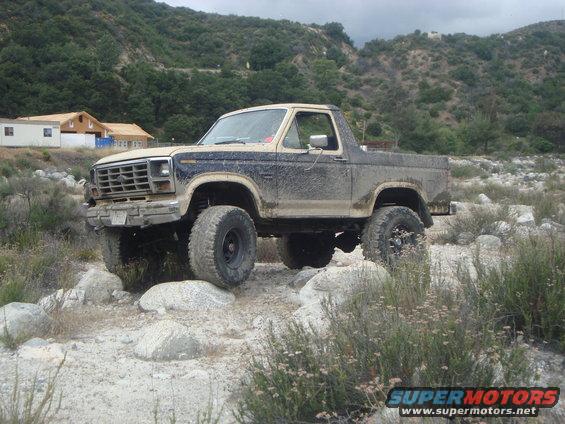 1986 Ford Bronco on rocky terrain, front right tire elevated