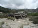 1986 Ford Bronco - Two off-road vehicles are parked in a rocky, mountainous area under a cloudy sky.