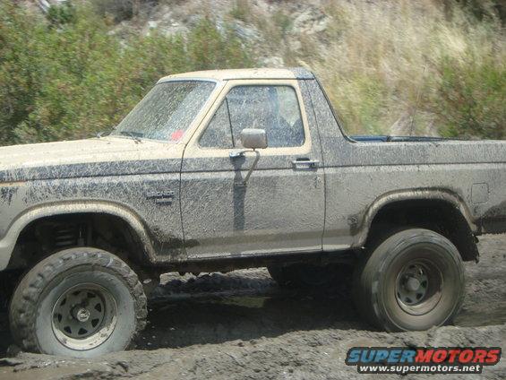 Mud-covered 1986 Ford Bronco side view, stuck in mud off-road