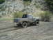 1986 Ford Bronco - This SUV is navigating a muddy trail, kicking up dirt and water as it goes.