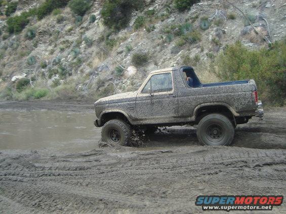 Muddy SUV driving through a muddy track with tires splashing