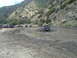 1986 Ford Bronco - Off-road vehicles navigate a muddy track in a scenic, hilly area.