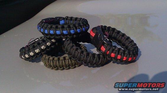 Four paracord bracelets with black buckles, one with blue accents, one with red accents, and one in olive drab
