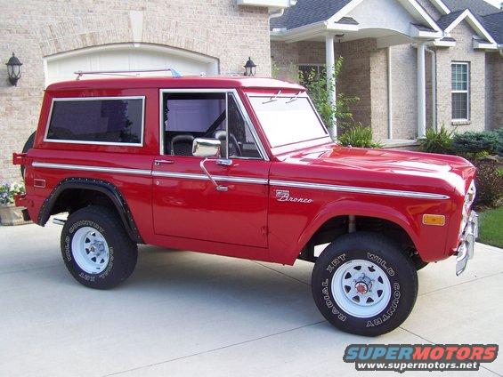 Red 1975 Ford Bronco parked in driveway, side view