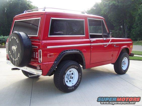 Red 1975 Ford Bronco, rear quarter view, with a spare tire on the tailgate and chrome trim