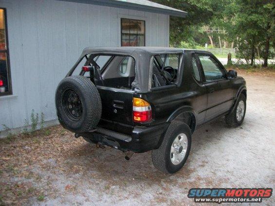 Black soft-top SUV with rear spare tire parked outdoors