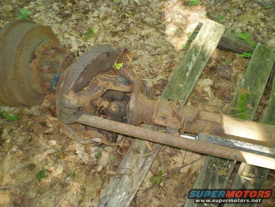 Rusted axle assembly with brake drum, lying on the forest floor