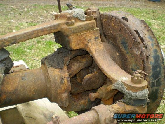 rusted front axle assembly with tie rods and brake drum