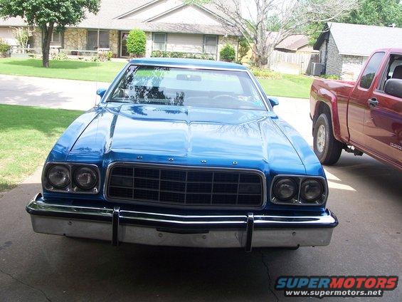 Front view of a blue 1977 Ford LTD II sedan parked in a driveway next to a red pickup truck