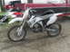 2007 Yamaha YZ450F - A white 2007 Yamaha YZ450F dirt bike is parked on a dirt surface, with a red truck behind it.