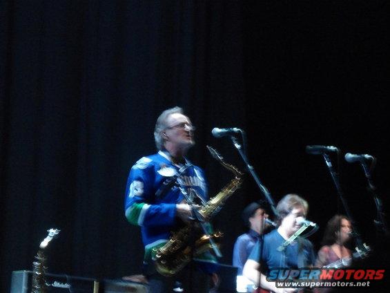 Musicians performing on stage with saxophones and guitars