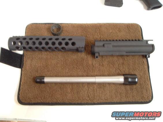 AR-15 upper receiver, handguard, and barrel laid out on a brown mat