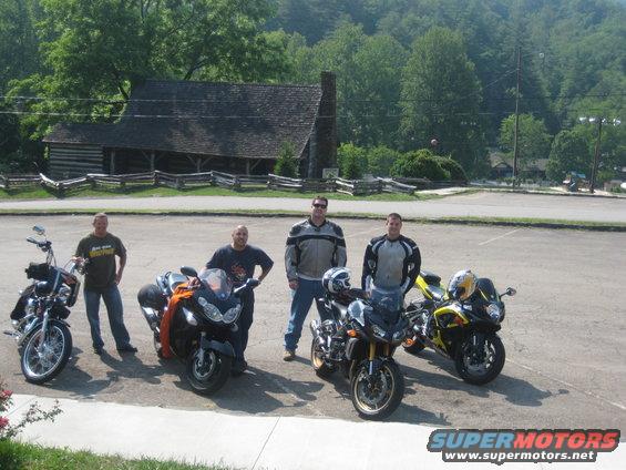 Four guys with their motorcycles parked in front of a rustic building