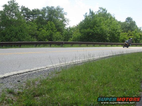 Motorcycle on a road with trees and guardrail