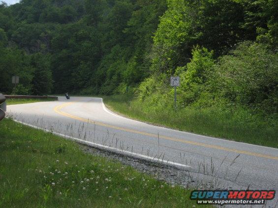 Motorcycle on a winding road with trees and grass
