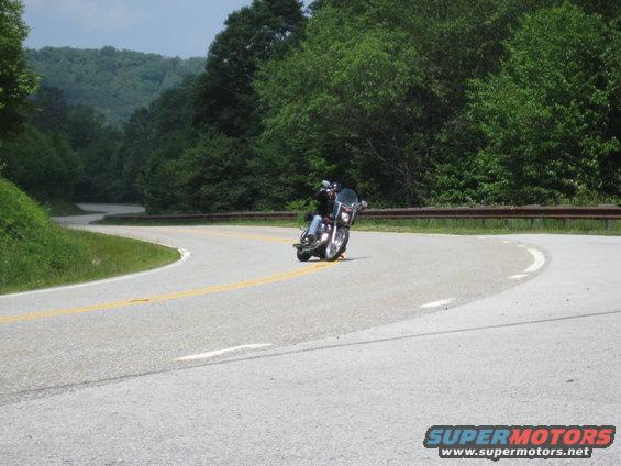 Motorcyclist leans into a curve on a tree-lined road
