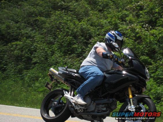 Black motorcycle with a rider wearing a blue and white helmet, seen from the side