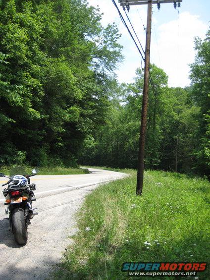 Motorcycle parked on a winding road with a utility pole