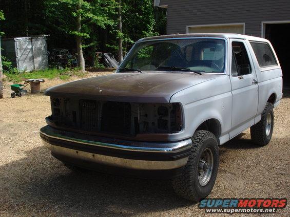 1993 Ford Bronco with missing grille and headlights, primer paint on hood