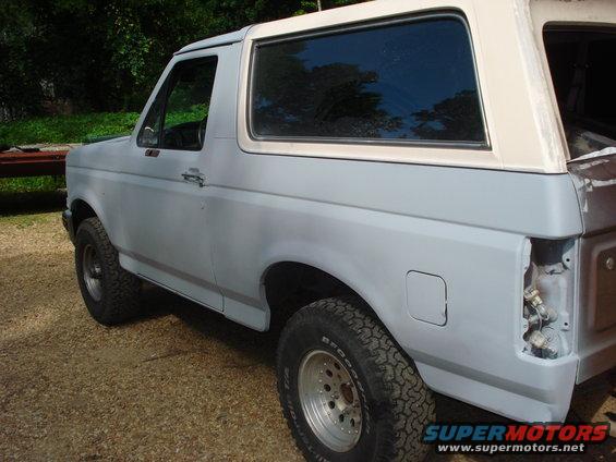 Gray Ford Bronco with a white top, primer finish, and missing taillight