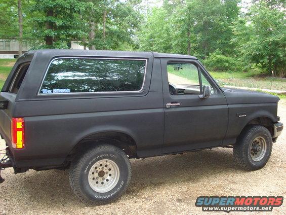 Black 1993 Ford Bronco parked on gravel, side view