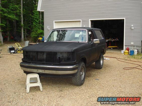 1993 Ford Bronco with matte black paint, grille removed, parked in driveway