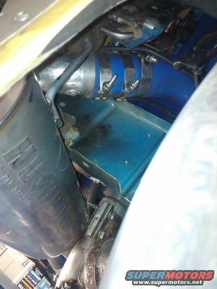Close-up of blue silicone hose with metal clamps and exhaust pipe with 'HUSH' visible