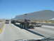 1993 Ford Taurus - A large wind turbine blade is transported on a flatbed truck down a highway, with a white pickup truck in front.