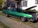 1973 Ford Ranchero - A green pickup truck sits in front of a house with its hood open, revealing the engine bay.
