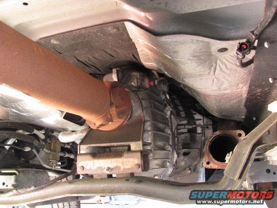 Underside view of a vehicle's drivetrain, showing the driveshaft and transmission housing