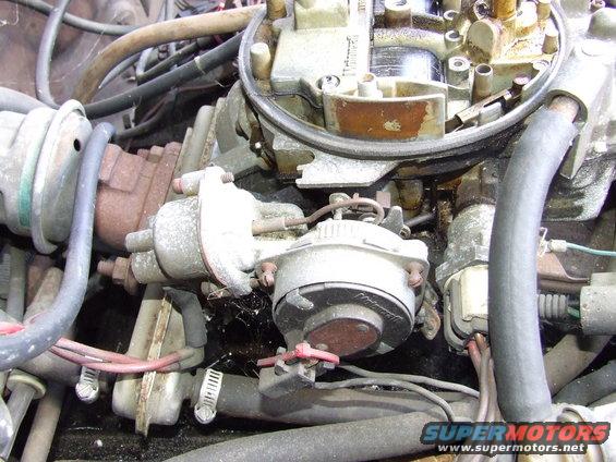 Close-up of a carburetor with hoses and wiring attached