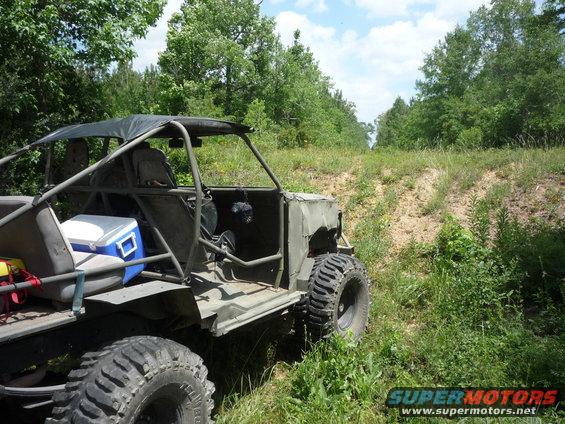 Custom off-road buggy with roll cage and large tires parked on a dirt path