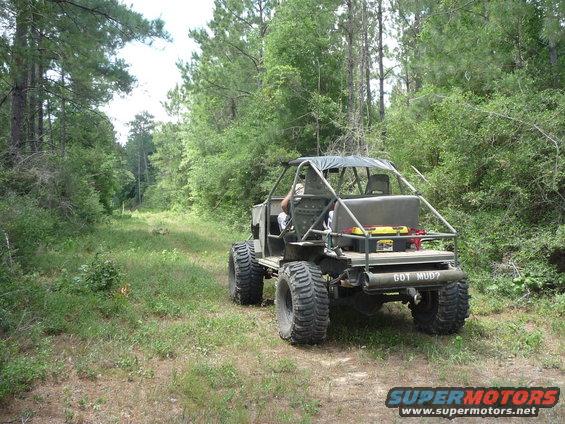 Off-road vehicle with large tires and 'GOT MUD?' on the back, driving on a dirt path