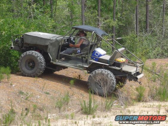 Man drives a custom military-style buggy with large tires off-road
