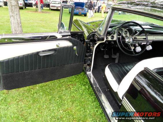 1956 Ford Fairlane interior showing black and white seats, door panel, and dashboard