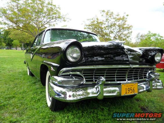 Black 1956 Ford Crown Victoria parked on grass, front quarter view. Yellow California license plate reads 1956