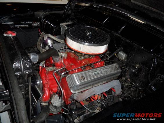 Engine bay of a 1956 Ford Fairlane with a red engine block, chrome valve covers, and an air filter