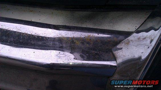 Close-up of a chrome bumper with rust and dirt. Supermotors.net logo visible