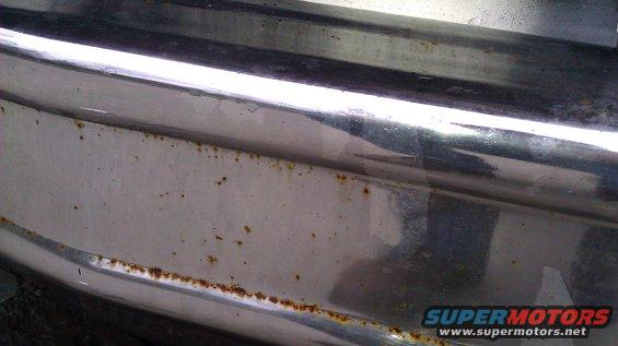 Close-up of a chrome bumper with rust spots along the bottom edge