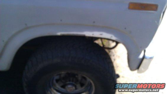 Gray 1980s SUV fender with visible rust spots and a large tire