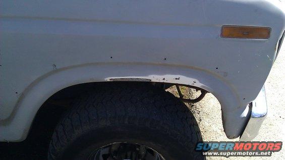 Fender rust on a light-colored vehicle's front wheel well