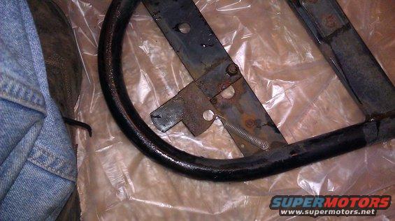 Close-up of a rusty metal spare tire mount bracket with a spring