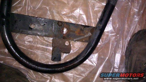 Spare tire rack bracket with spring and rust, on plastic sheeting