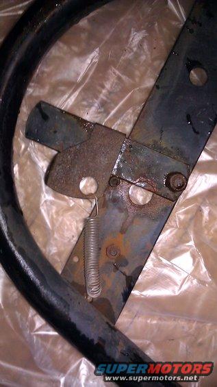 Close-up of a rusty metal spare tire rack mechanism with a spring