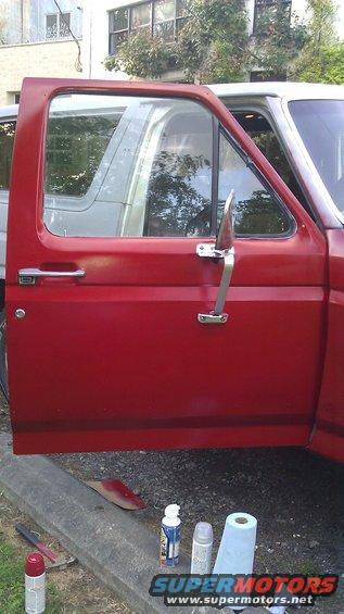 red truck door open, showing interior and another vehicle reflected in window