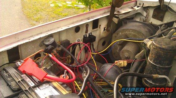 close-up of engine bay with battery, wires, and relays