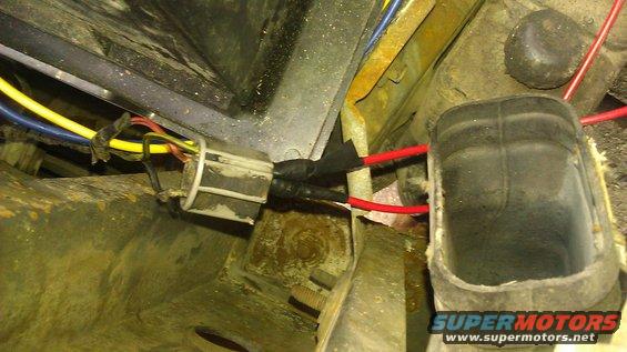 Wiring harness with yellow, blue, and red wires connected to a grey connector, with black tape and red wires extending from it