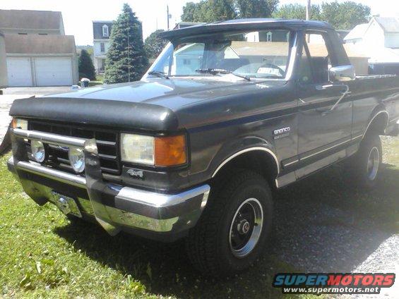 Dark gray Ford Bronco with a chrome grille guard and auxiliary lights