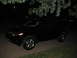 2009 Nissan Murano - A black SUV is parked on a paved surface at night, with tree branches overhead.